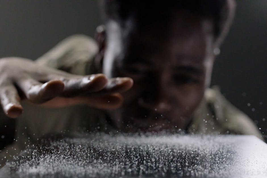 A close-up shot of a man focusing on water drops with his hand extended.