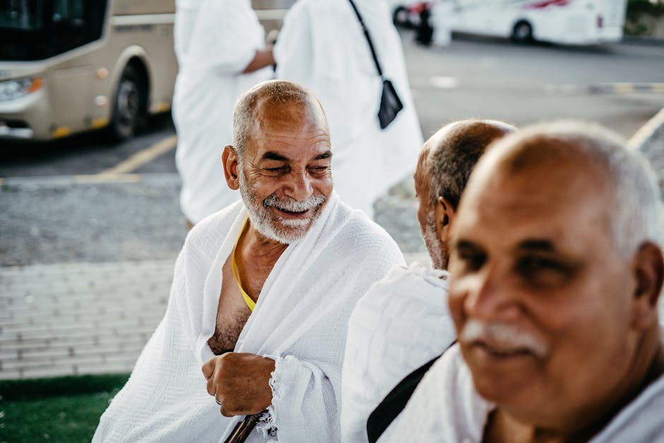 Senior men in white robes share a joyful moment outdoors, expressing happiness and camaraderie.