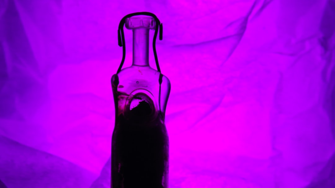 A bottle silhouette lit by bright purple light.