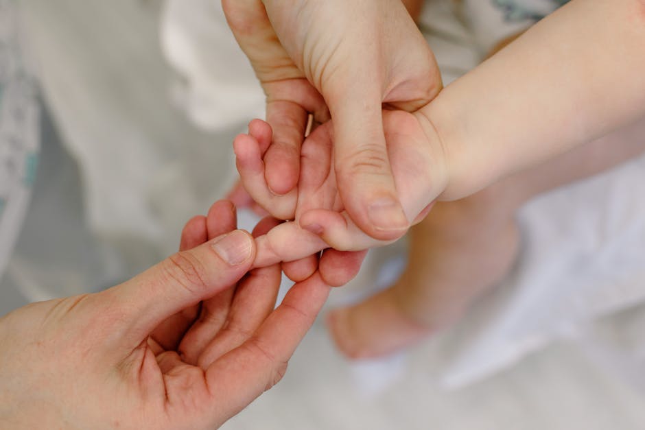 Close-up of an adult giving a gentle massage to a baby's hand, showcasing tender care and nurturing touch.