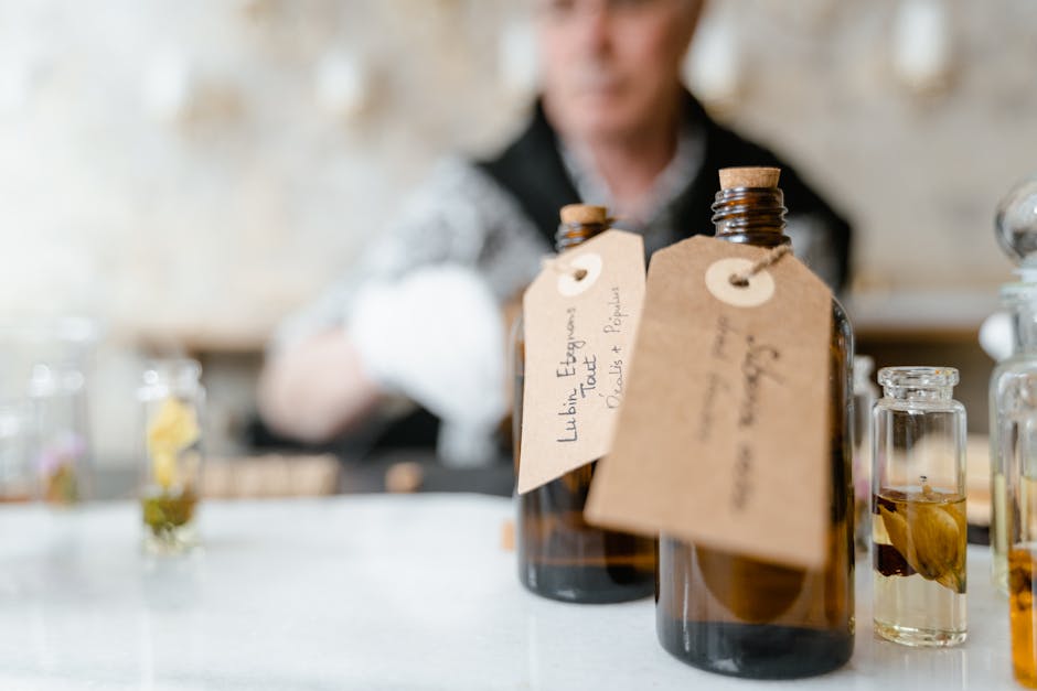 Artisan perfume bottles with handwritten tags on a table, blurred person in background.