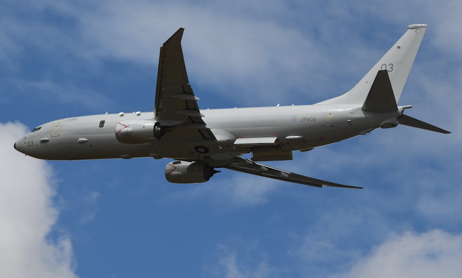 Military aircraft flying over England, showcasing aviation technology against blue sky.