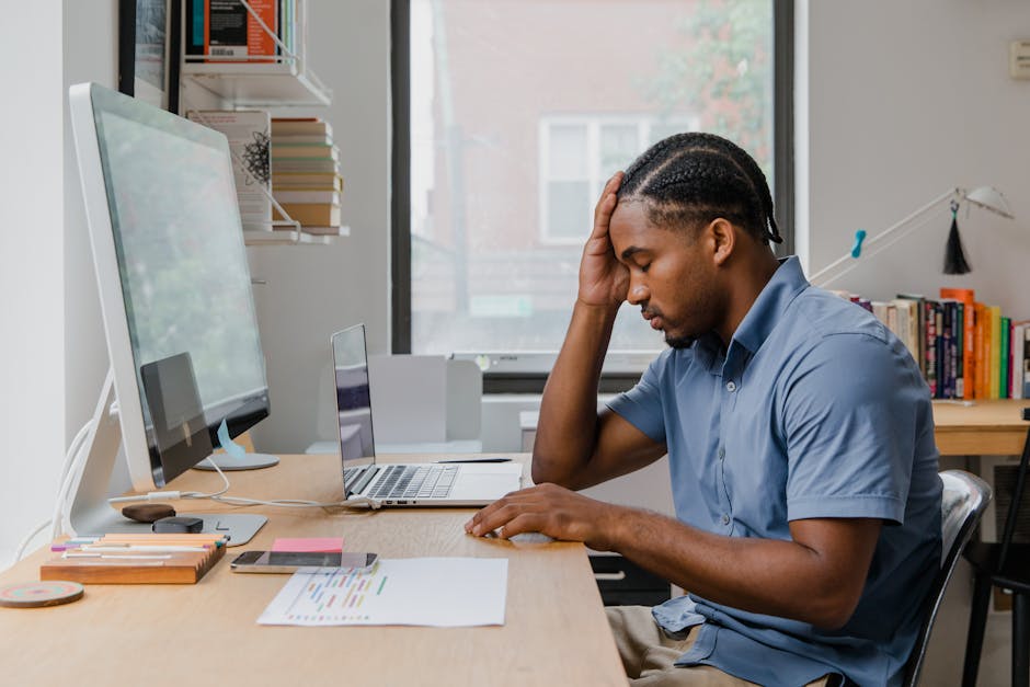 A man appears overworked in an office setting, showing stress at his desk.