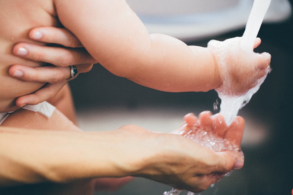 Heartwarming close-up of a parent gently washing a baby's hand under running water.