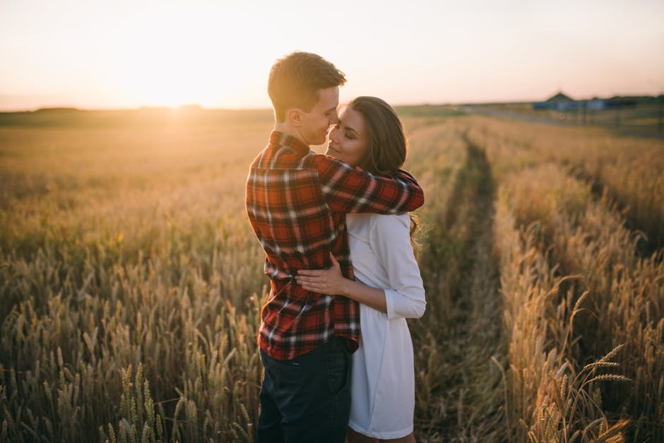 A loving couple embracing in a golden wheat field during sunset, creating a serene and romantic atmosphere.