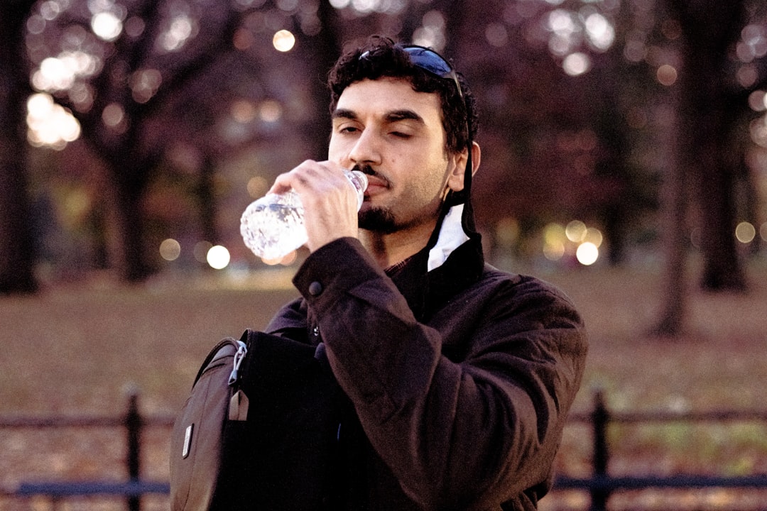 man in black jacket drinking water