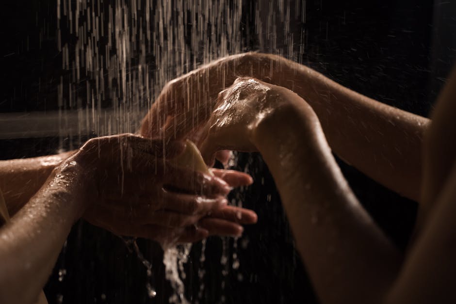 Close-up of hands washing under a shower, emphasizing cleanliness and care.