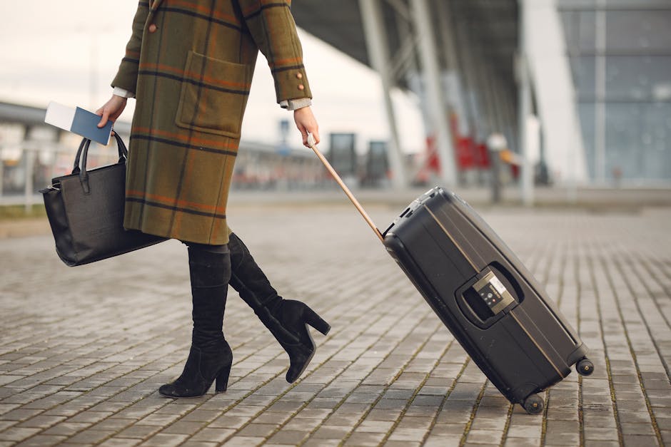 A fashionable woman in a coat walks with luggage and a handbag outdoors. Ideal travel concept.