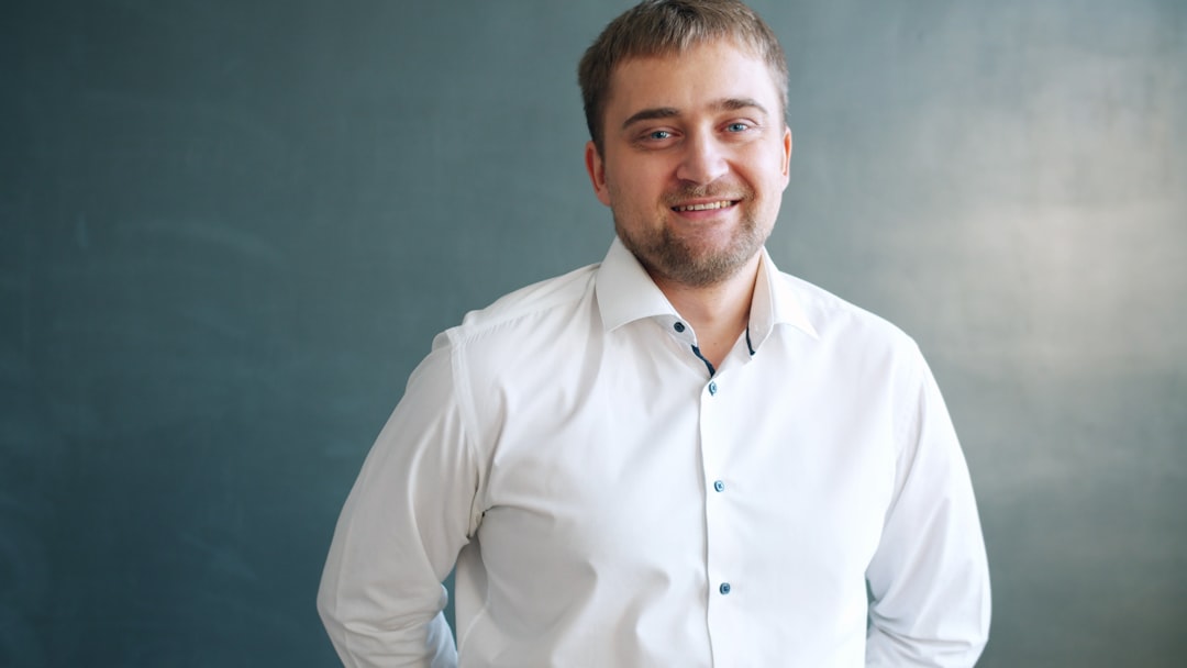 A smiling man in a white collared shirt.