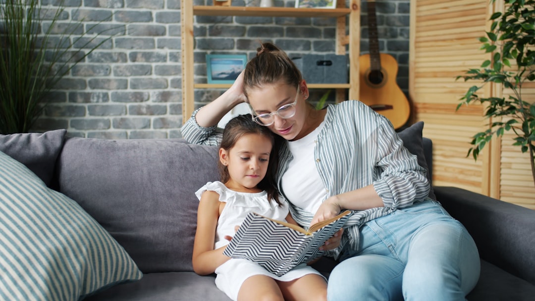 Mother and daughter reading a book together on the couch.