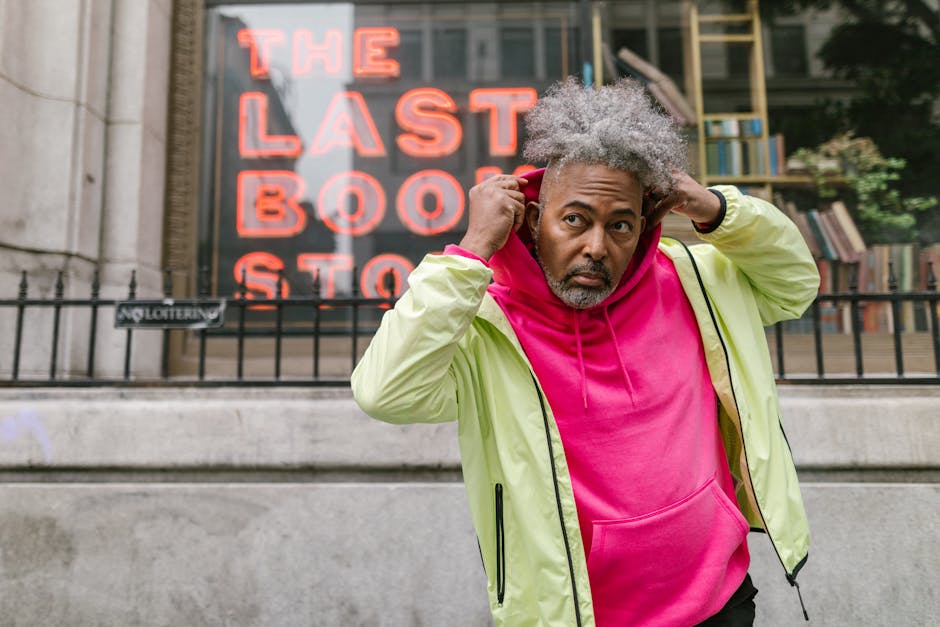 A middle-aged man poses confidently in vibrant streetwear outside a city bookstore.
