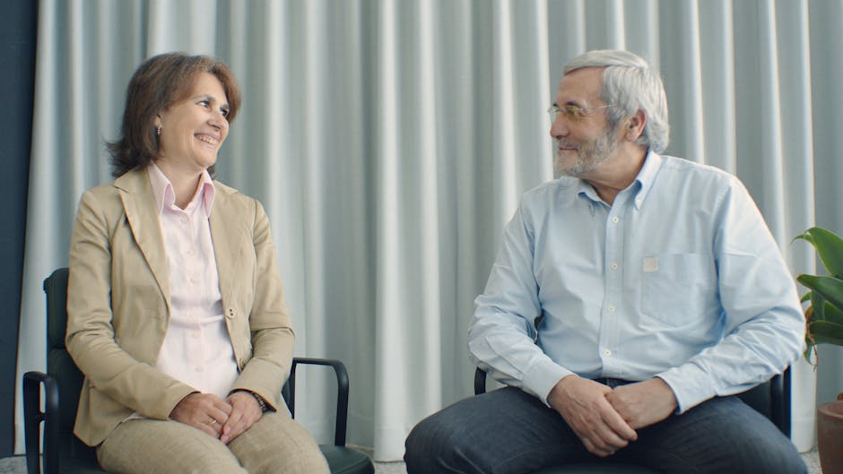 Smiling elderly couple sitting indoors in a room with curtains, Portugal.