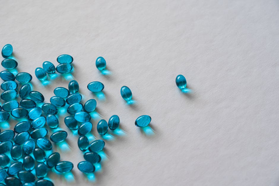 High angle view of scattered blue gel capsules on a flat white surface.