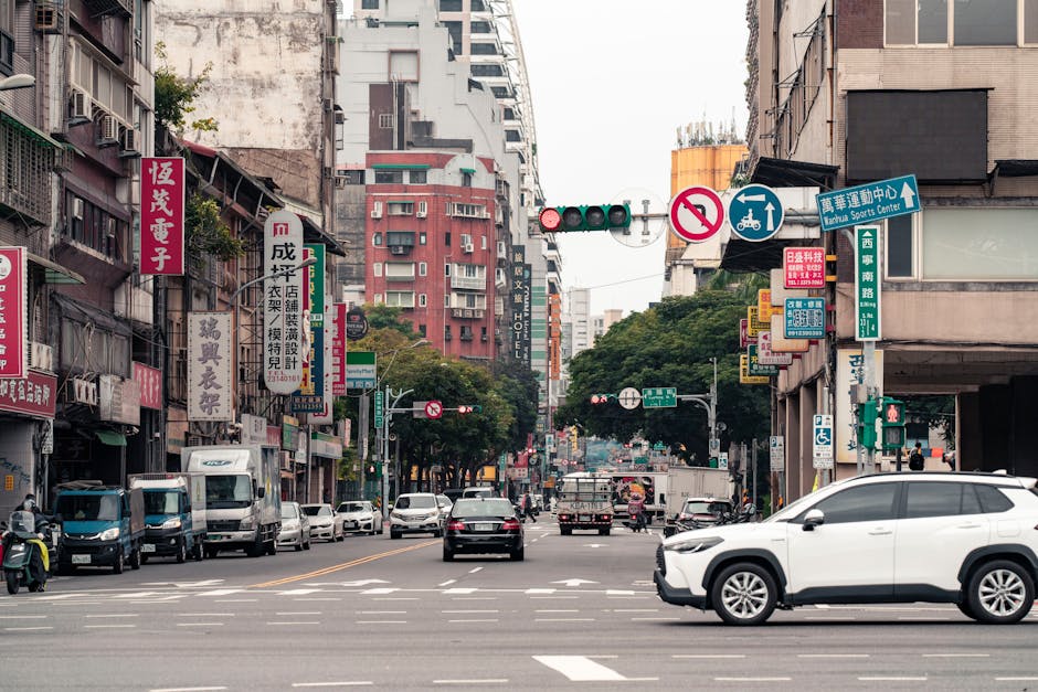 Lively urban street in Taipei, Taiwan, featuring cars, bikes, and vibrant Chinese signs.