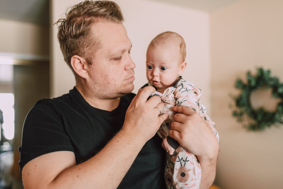 Man holding a baby indoors, displaying a loving bond and family togetherness.