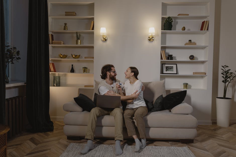 Smiling couple enjoying time together on a sofa in a stylish, cozy living room setting.
