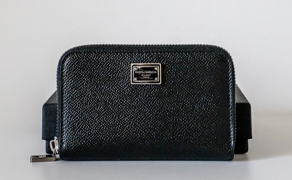 Elegant black leather wallet with metallic logo plate, ideal for fashion enthusiasts.