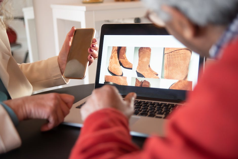 Two people shopping for shoes online using a laptop and smartphone at home.